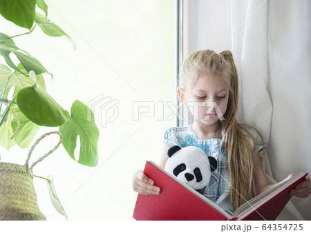Sad child girl by the window Sad child girl by the window 64354725