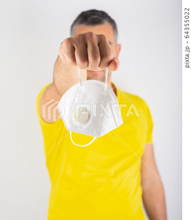 A man in yellow t-shirt holds medical mask. Coronavirus concept. Protect your health. 64355022