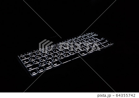 暗闇で光るパソコンのキーボードの写真素材