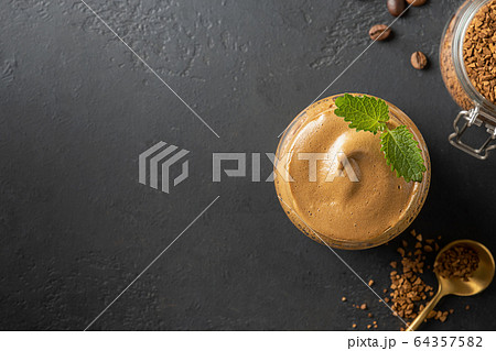 Dalgona frothy coffee in glass on black.  64357582