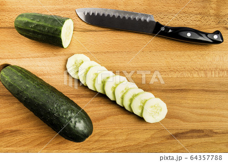 Whole and cut green cucumbers next to a knife Whole and cut green cucumbers next to a knife 64357788