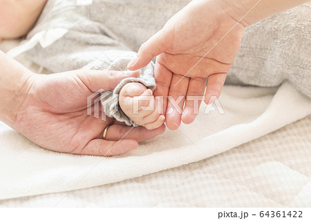 明るい部屋の中で赤ちゃんの手を握る両親の手の写真素材