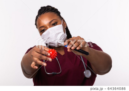 Covid-19, Vaccine development , outbreak and medicine concept - Doctor in medical protective mask holding a model of coronavirus and test tube on white background. Covid-19, Vaccine development , outbreak and medicine concept - Doctor in medical protective mask holding a model of coronavirus and test tube on white background. 64364086