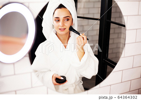 Pretty woman doing cosmetic procedures to care for face skin in bathroom Pretty woman doing cosmetic procedures to care for face skin in bathroom 64364302