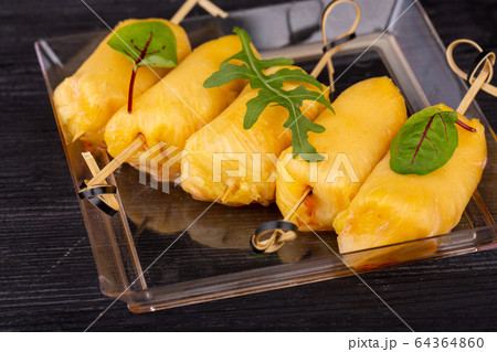 Canape of fresh pineapple wrapped with cheese and greens 64364860