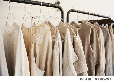 Close up of a selection of clothes in natural colours on a rail in a boutique. Close up of a selection of clothes in natural colours on a rail in a boutique. 64365204