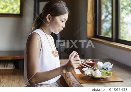 Japanese woman sitting at a table in a Japanese restaurant, eating. 64365433