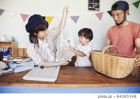 Japanese man, woman and boy standing in a farm shop, sorting clear plastic bottles into basket. 64365548