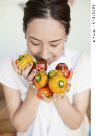 High angle close up of Japanese woman holding freshly picked picked red and yellow peppers. 64365591