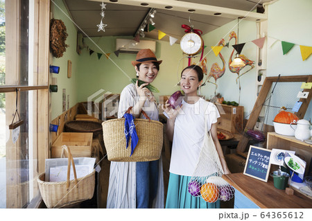 Two smiling Japanese women standing in a farm shop, looking at camera. 64365612
