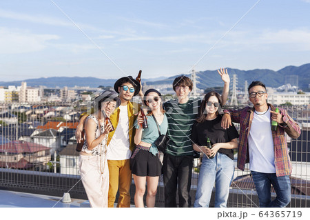 Group of young Japanese men and women standing on a rooftop in an urban setting. 64365719
