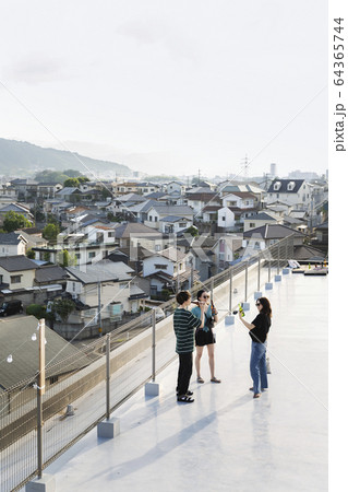 High angle view of group of young Japanese men and women standing on a rooftop in an urban setting. 64365744
