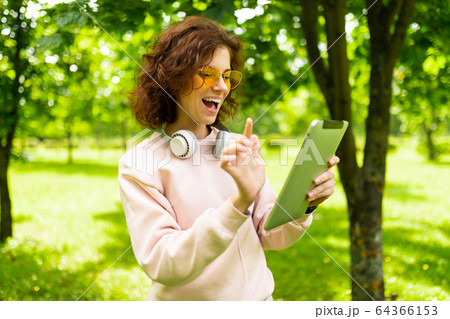 Pretty young caucasian woman is engaged in freelance in the park with laptop 64366153