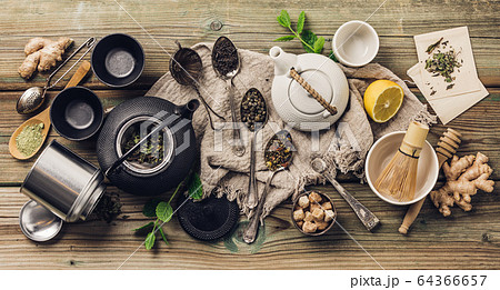Various tea and teapots composition, dried herbal, green, black tea and matcha tea on wooden table background 64366657