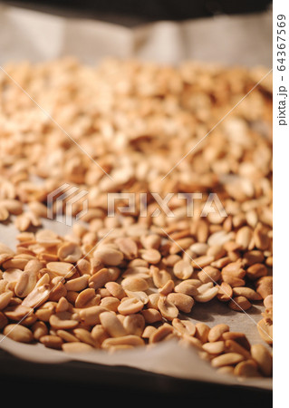 Peanut beans are fried on baking sheet and parchment paper in the oven. Preparing to make homemade peanut butter at home. Peanut beans are fried on baking sheet and parchment paper in the oven. Preparing to make homemade peanut butter at home. 64367569