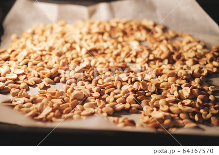 Peanut beans are fried on baking sheet and parchment paper in the oven. Preparing to make homemade peanut butter at home. Peanut beans are fried on baking sheet and parchment paper in the oven. Preparing to make homemade peanut butter at home. 64367570