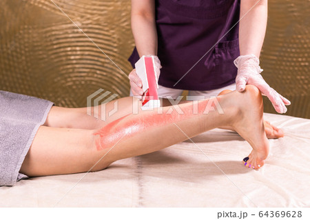 Waxing woman leg. Salon wax beautician epilation procedure. Waxing female body for hair removal by therapist close up. Smooth legs concept. 64369628