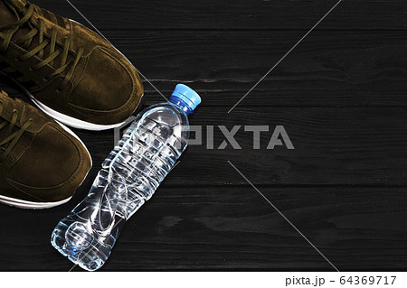 sneakers and a bottle of water on a black wooden background. The concept of a healthy lifestyle 64369717