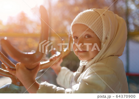 Cute girl riding a carousel holding deer horns 64370900