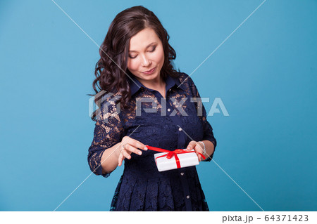 Beautiful Asian woman opens gift red ribbon Beautiful Asian woman opens gift red ribbon 64371423