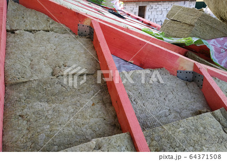 The worker insulates the roof with a mineral wool. 64371508