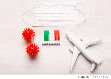 Plane model and face mask and flag Italy. Coronavirus pandemic. Flight ban and closed borders for tourists and travelers with coronavirus covid-19 from Europe and Asia. 64372495