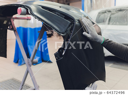 Auto mechanic preparing the car for paint job by applying polish with the power buffer machine 64372496
