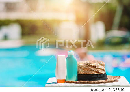 Suncream bottles, goggles, starfish on the edge of the pool Suncream bottles, goggles, starfish on the edge of the pool 64373404