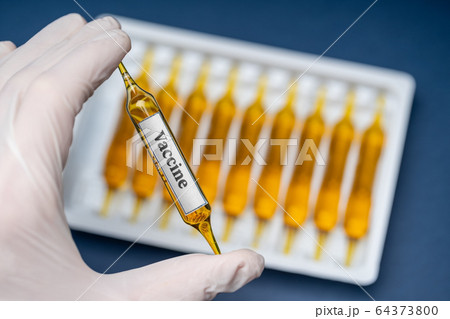 Medical capsules vaccine from coronavirus virus on the table and in hand on a blue background. 64373800