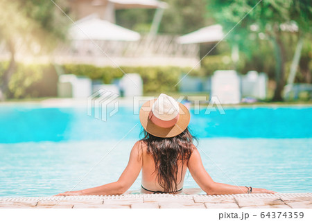 Young beautiful woman enjoying summer vacation in luxury swimming pool 64374359