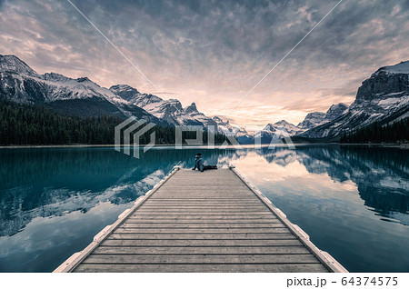 Traveler relaxing on wooden pier in Maligne lake Traveler relaxing on wooden pier in Maligne lake 64374575
