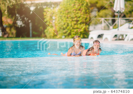 Adorable little girls playing in outdoor swimming pool on vacation 64374810