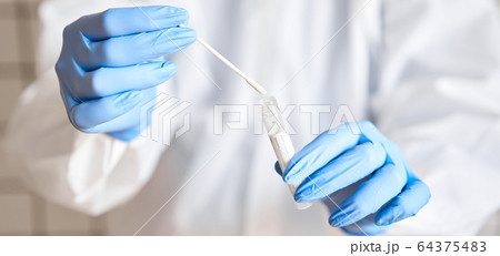 Doctor holding swab test tube for 2019-nCoV analyzing. Coronavirus test. Blue medical gloves and protective face mask for protection against covid-19 virus. Coronavirus and pandemic. Doctor holding swab test tube for 2019-nCoV analyzing. Coronavirus test. Blue medical gloves and protective face mask for protection against covid-19 virus. Coronavirus and pandemic. 64375483