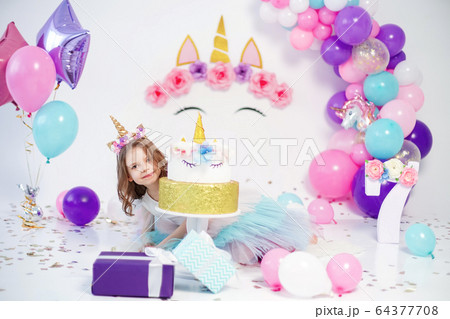 Unicorn Girl posing near happy birthday cake. Idea for decorating unicorn style birthday party. Unicorn decoration for festival party girl Unicorn Girl posing near happy birthday cake. Idea for decorating unicorn style birthday party. Unicorn decoration for festival party girl 64377708