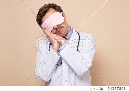 Young caucasian male doctor with sleeping mask on Young caucasian male doctor with sleeping mask on 64377808