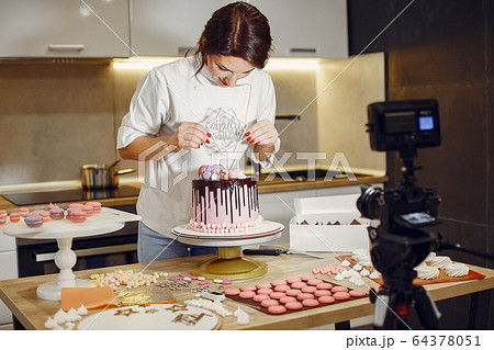 Confectioner in a uniform decorates the cake Confectioner in a uniform decorates the cake 64378051