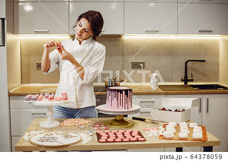 Confectioner in a uniform decorates the cake 64378059