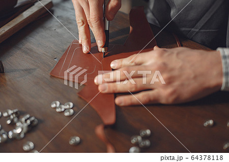 Man in a studio creates leather ware Man in a studio creates leather ware 64378118