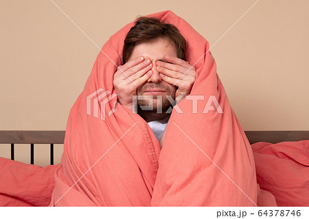 Scared young man covering face in stress sitting 64378746