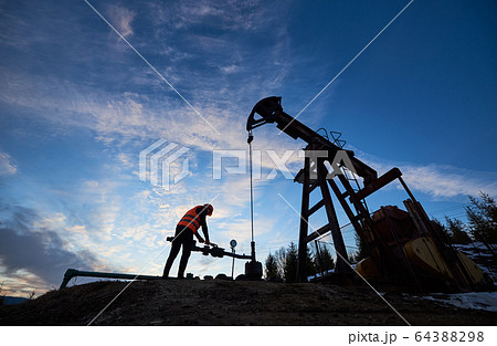Oil man working in oil field with pump jack. Oil man working in oil field with pump jack. 64388298