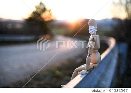 Wooden mannequin with face mask by road, corona virus and lockdown concept. Wooden mannequin with face mask by road, corona virus and lockdown concept. 64388547