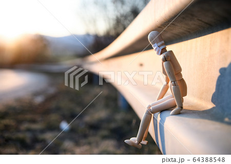 Wooden mannequin with face mask by road, corona virus and lockdown concept. 64388548