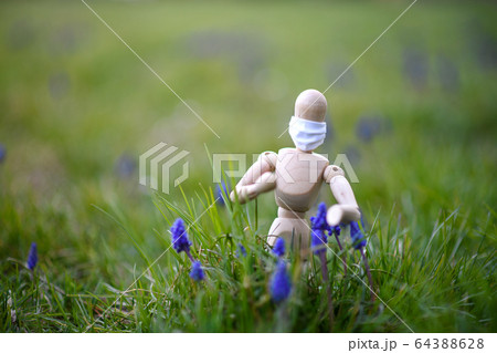 Wooden mannequin with face mask in nature, corona virus and lockdown concept. Wooden mannequin with face mask in nature, corona virus and lockdown concept. 64388628