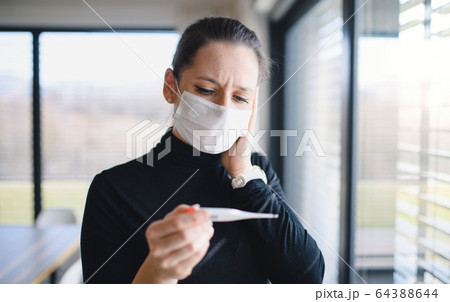 Worried woman with thermometer and face masks indoors at home, Corona virus concept. 64388644