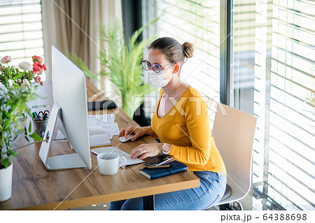 Woman working indoors at home office, Corona virus and quarantine concept. Woman working indoors at home office, Corona virus and quarantine concept. 64388698