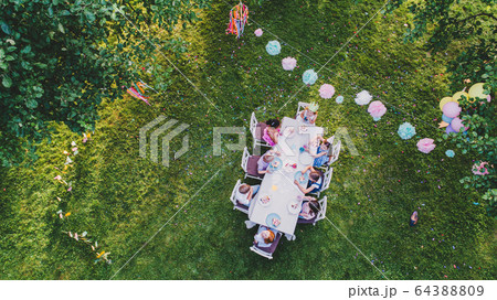 Aerial view of small children sitting at table on summer garden party. 64388809