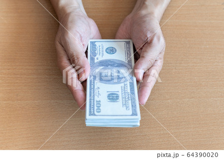Man hands holding 100 dollar bills on wooden Man hands holding 100 dollar bills on wooden 64390020