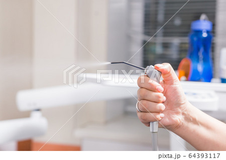 Dentistry, dental health and medicine concept - Close-up of dentist's hand holding a dental tool instrument. Dentistry, dental health and medicine concept - Close-up of dentist's hand holding a dental tool instrument. 64393117