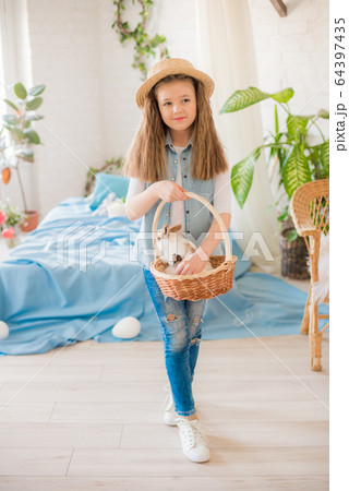 Cute girl with easter bunnies in the room decorative for the holiday. Easter mood Cute girl with easter bunnies in the room decorative for the holiday. Easter mood 64397435