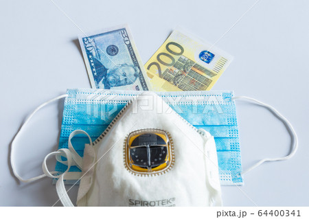Banknotes of American and European currency under a medical mask. 64400341
